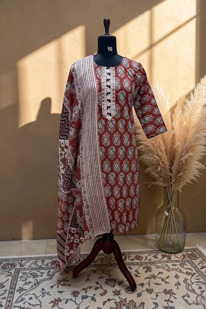 A red and white printed kurta displayed on a black mannequin dress form, set against a warm beige wall with decorative pampas grass in a glass vase.